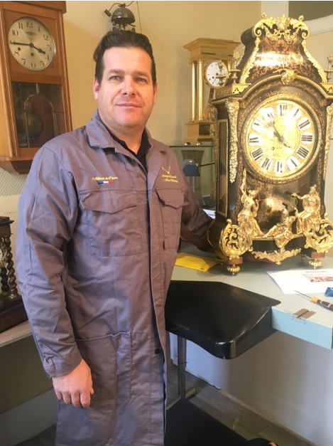 Un homme à côté d'une pendule.