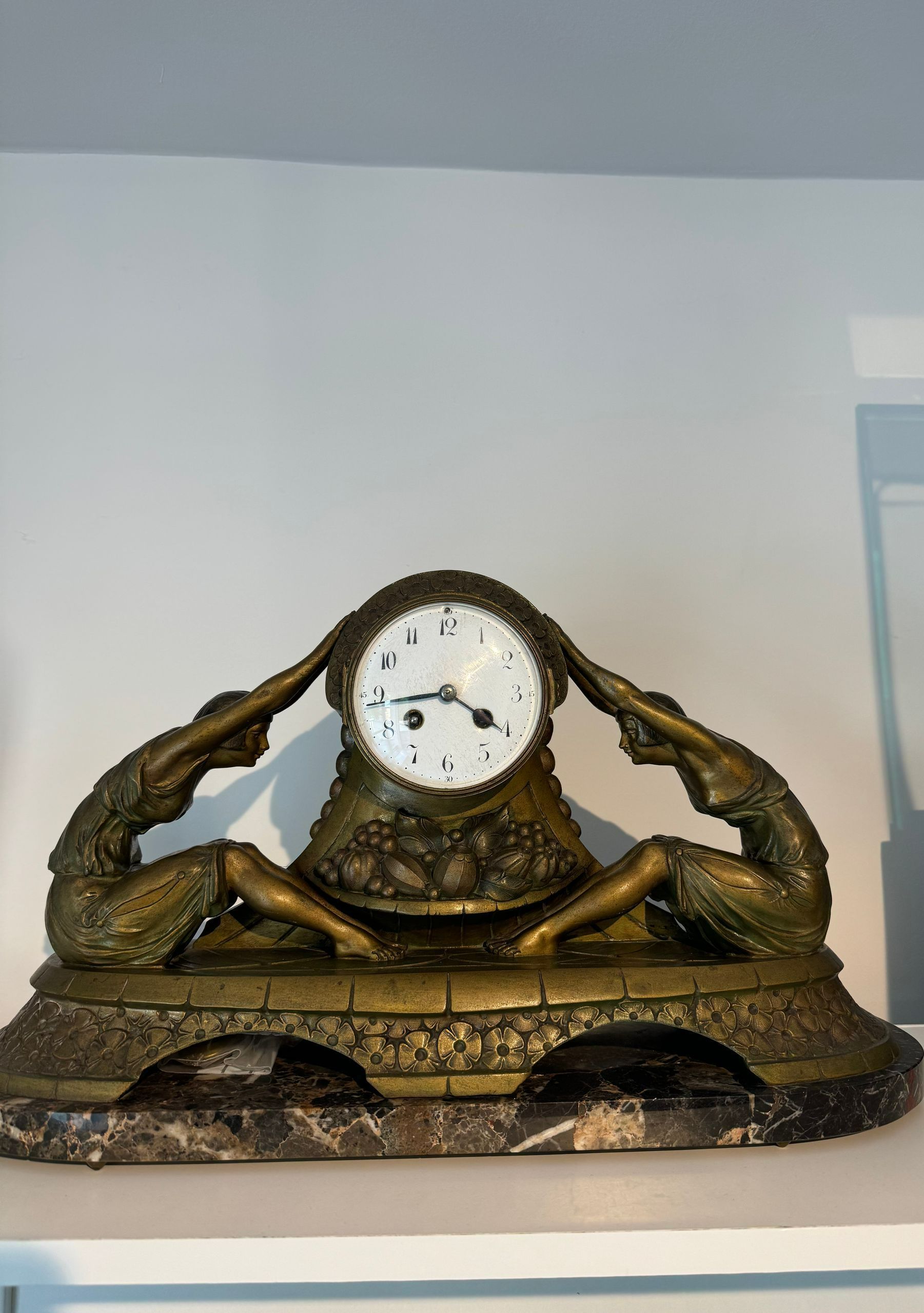 Une horloge en bronze avec deux sculptures dessus.