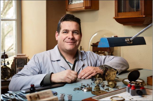 Un homme devant des mécanismes d'horlogerie.