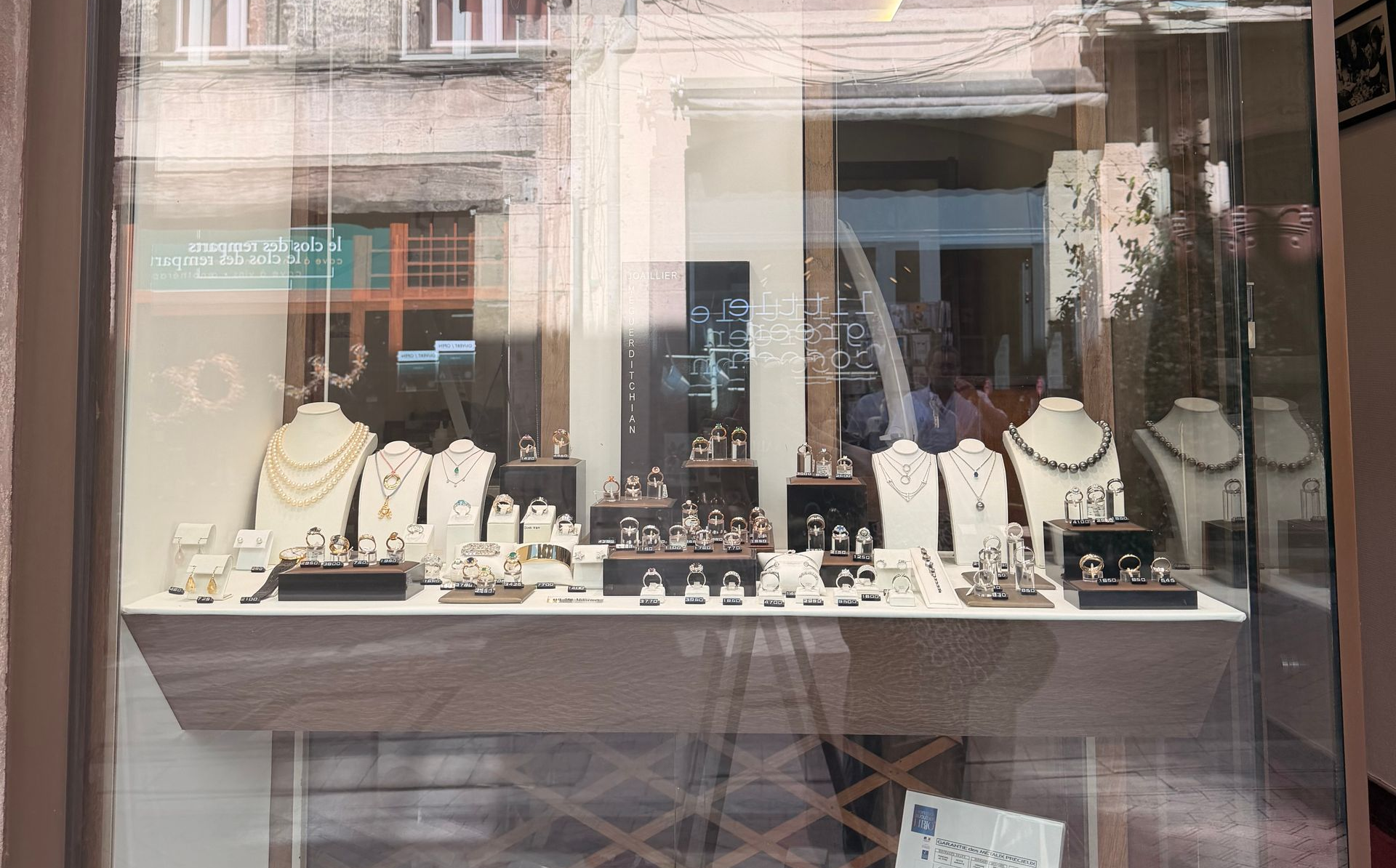 Vitrine de bijouterie présentant des colliers et des bagues sur des supports noirs.