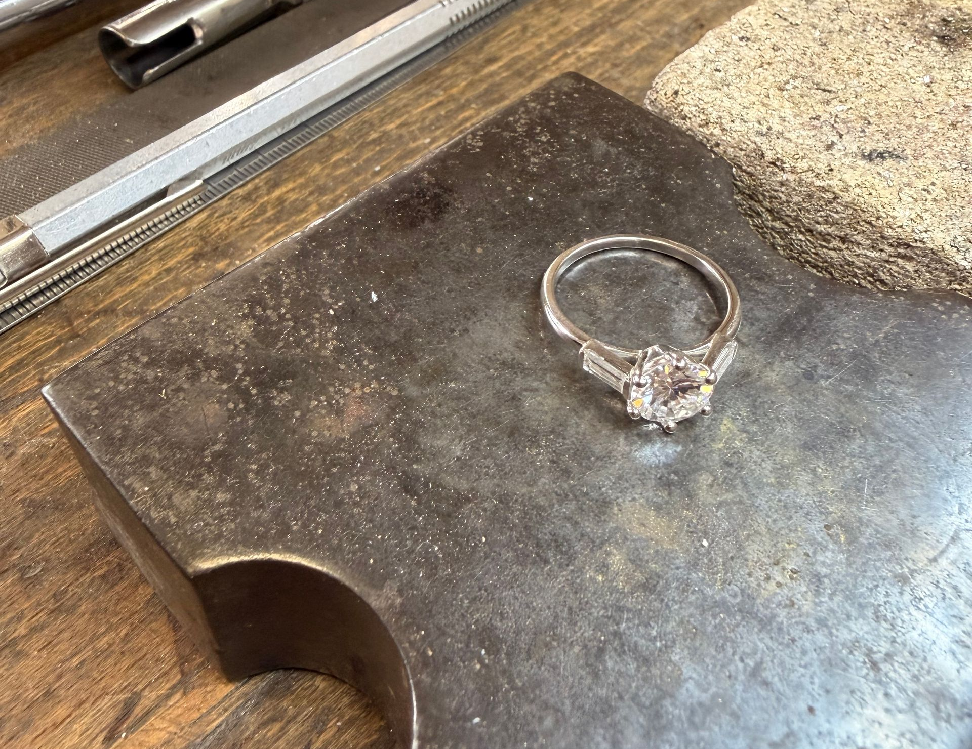 Gros plan sur une bague en or blanc et diamant dans un atelier de joaillerie.