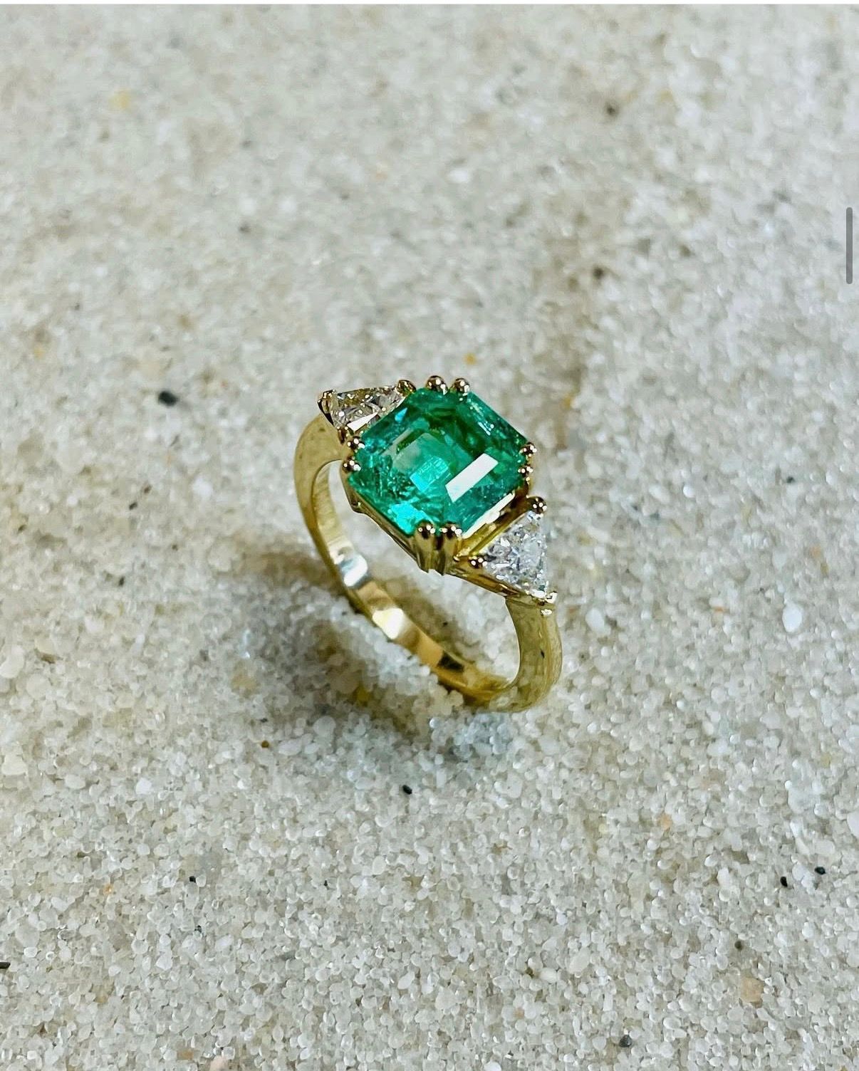 Bague ornée d'une émeraude avec deux diamants format triangle.