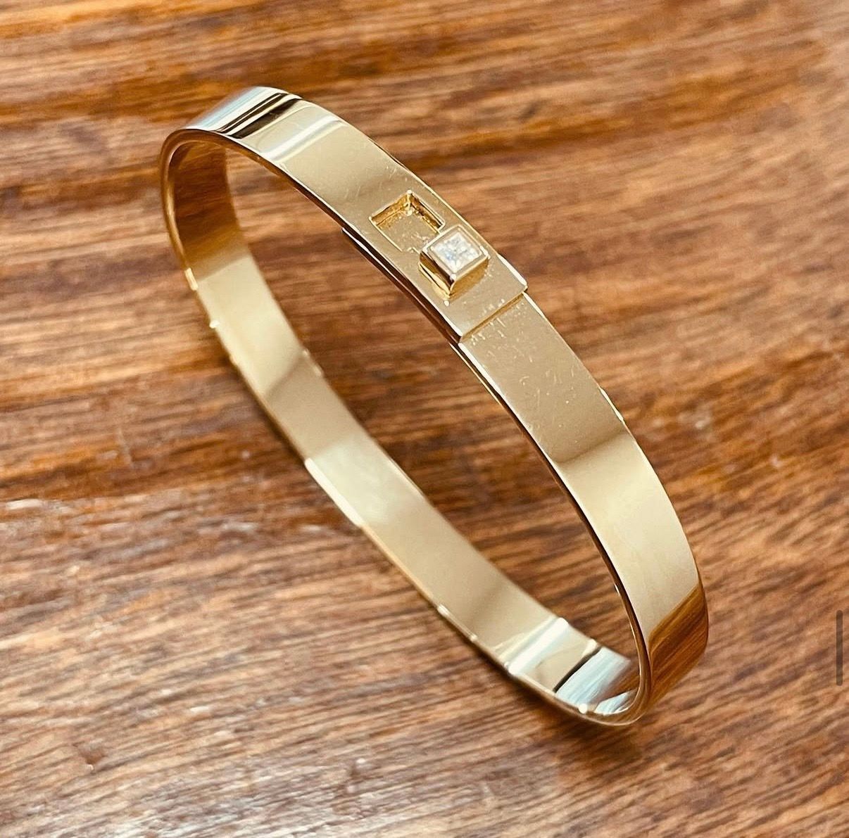 Bracelet en or ouvrant, avec système de serrure et diamant taille princesse.