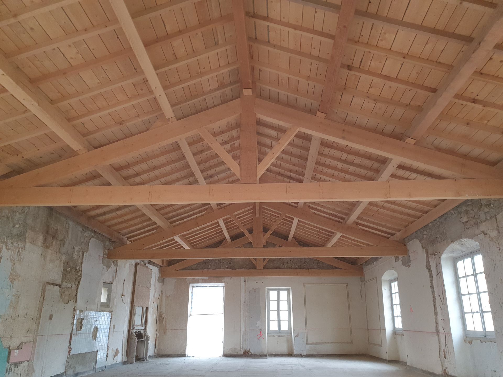 Rénovation d'une charpente d'un ancien bâtiement aux fenêtres arrondies