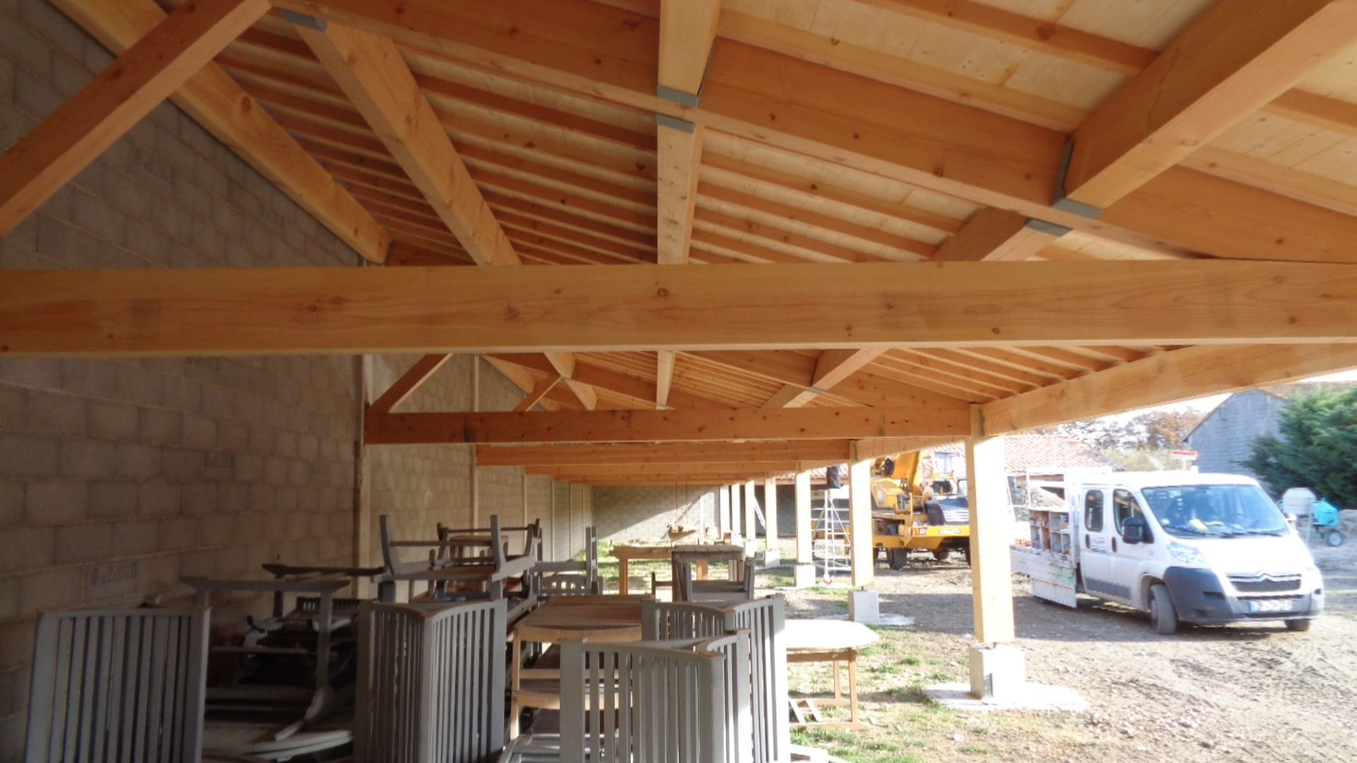 Grand avant-toit en bois contre un bâtiment en moellons