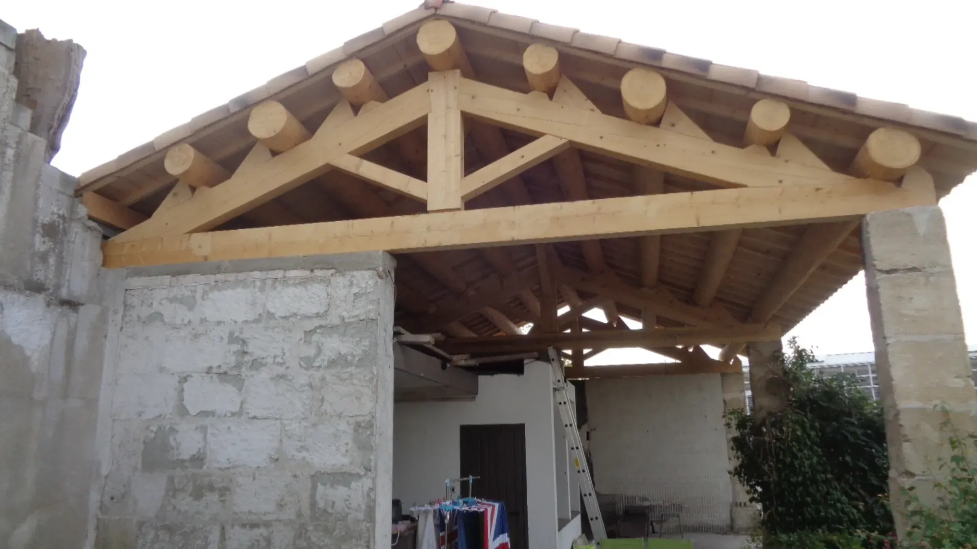 Charpente d'un garage avec des poutres rondes