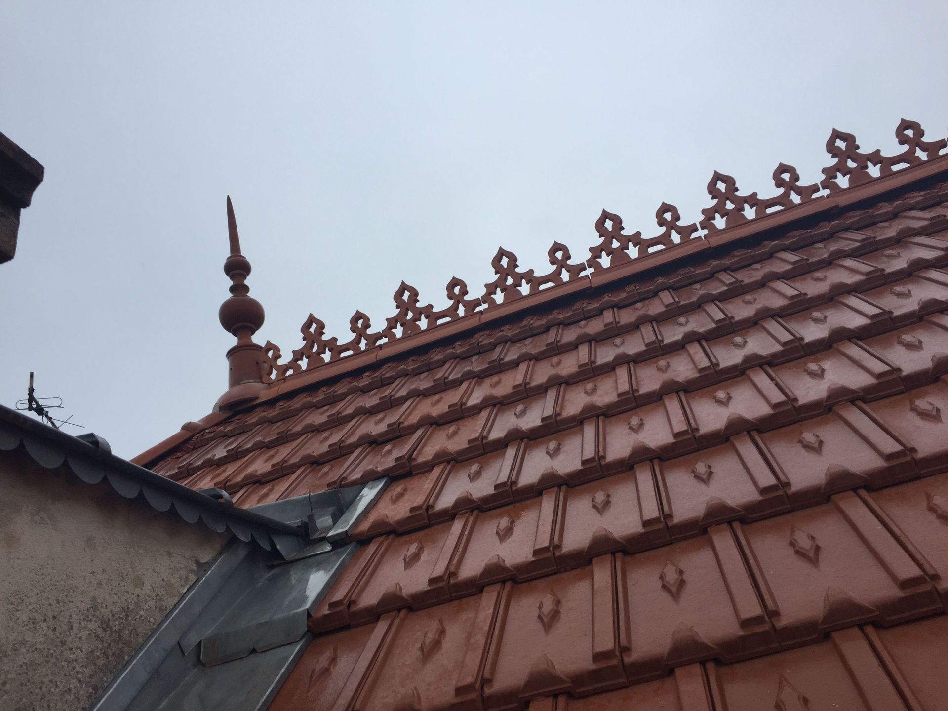 Toiture en pente, avec des tuiles ornementées et une décoration sur le haut