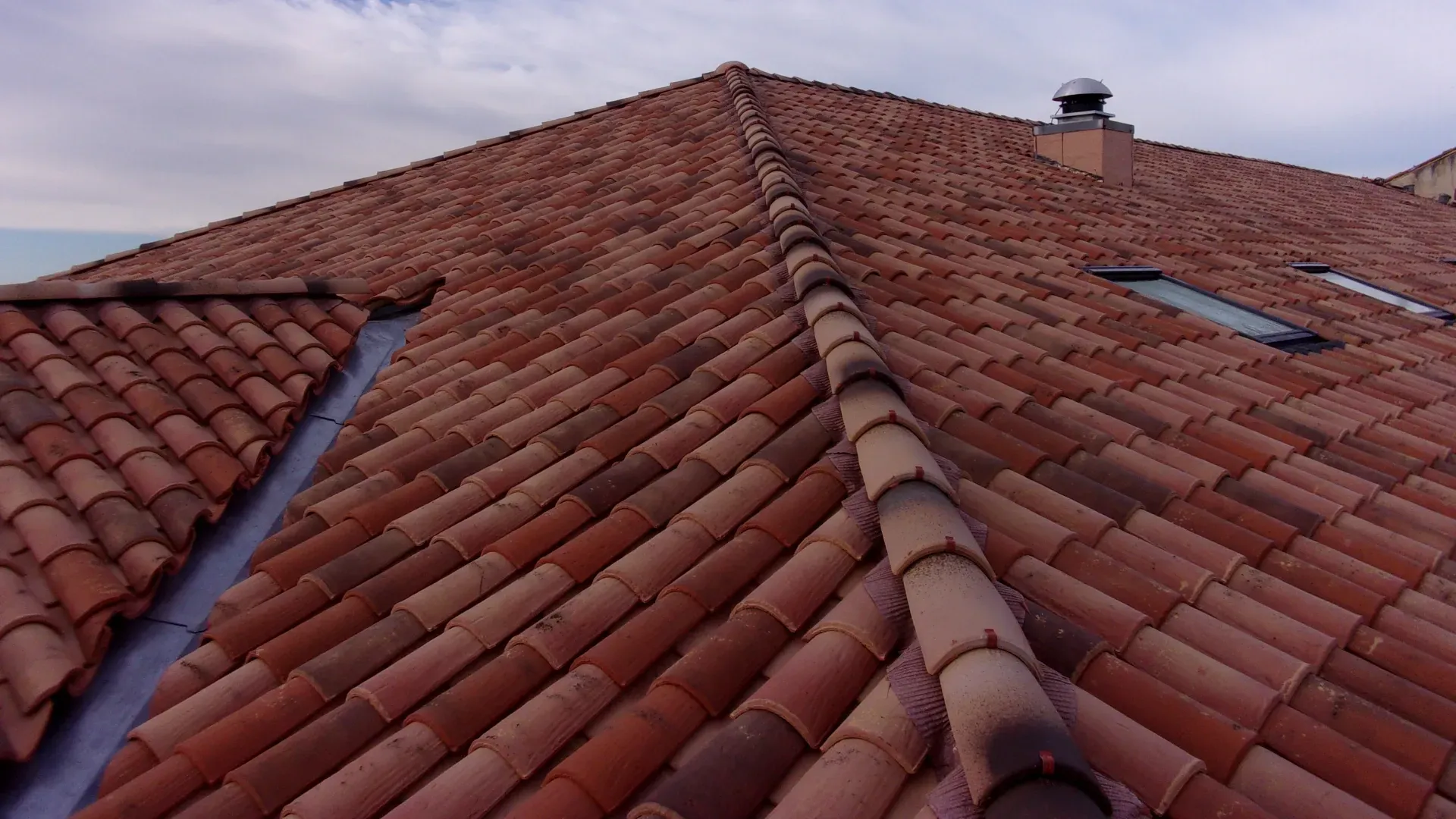 Grande toiture en tuile avec 2 fenêtres de toit et une cheminée