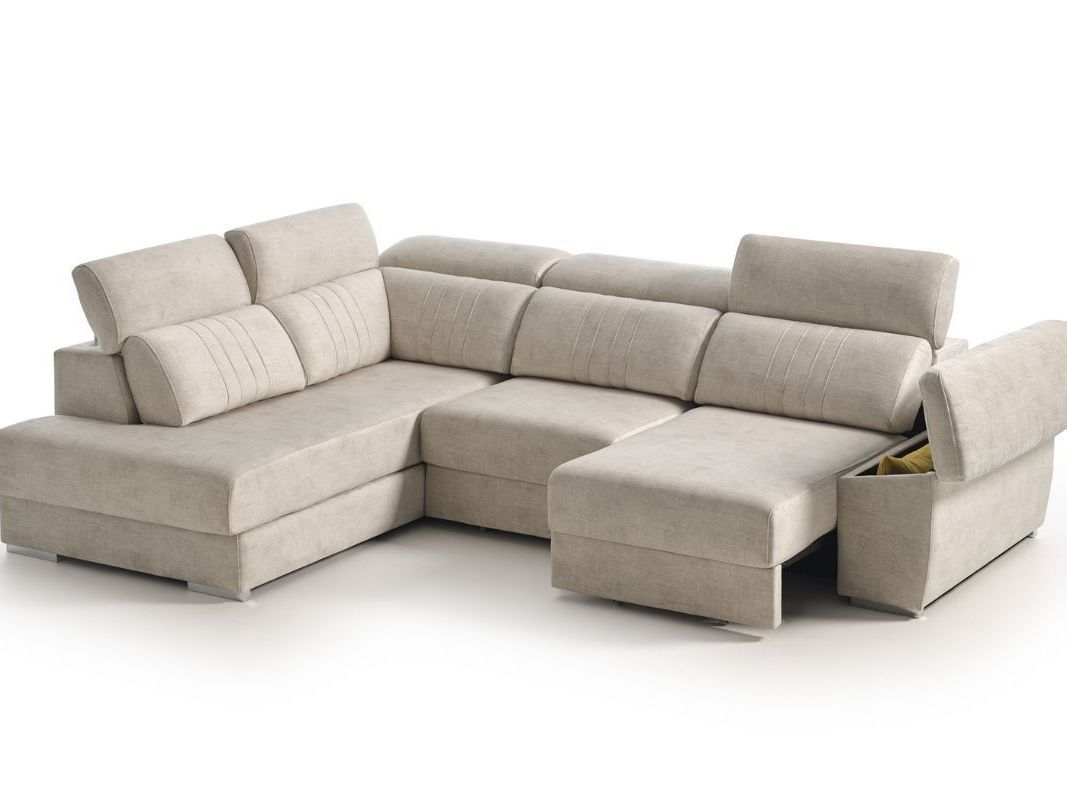 Un sofá seccional beige con una otomana debajo sobre un fondo blanco.