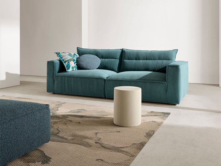 Una sala de estar con un sofá azul y un taburete blanco.