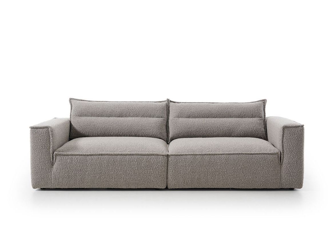 Un sofá gris con dos almohadas sobre un fondo blanco.