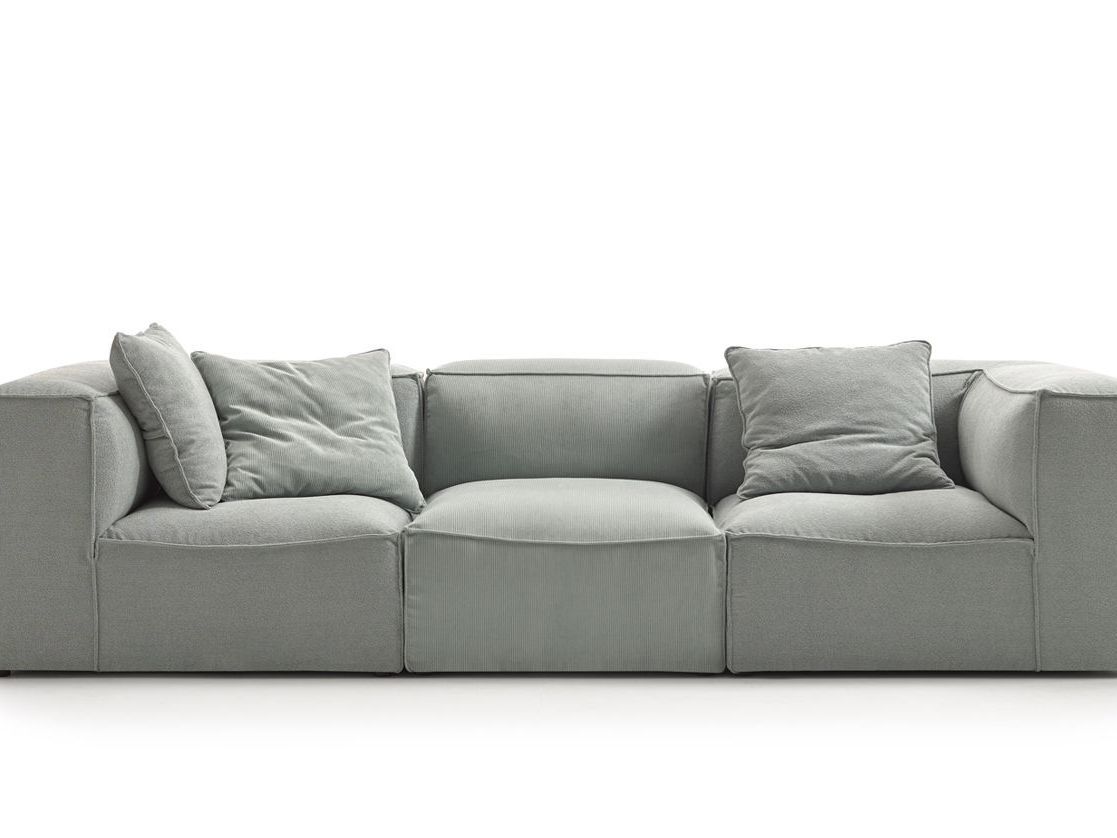 Un sofá gris con almohadas sobre un fondo blanco.