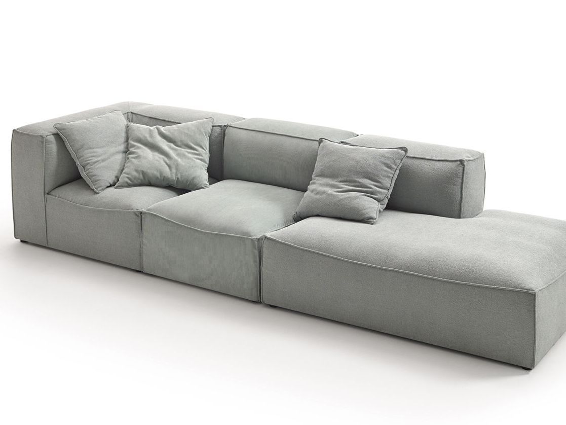 Un sofá gris largo con almohadas sobre un fondo blanco.