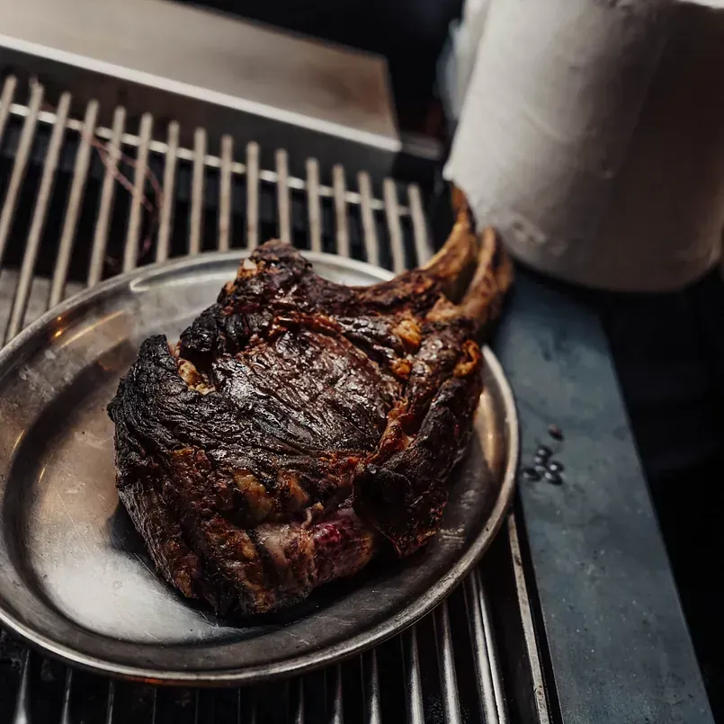 Un gran trozo de carne está sobre una placa de metal en una parrilla.