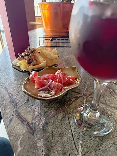 Un plato de comida y una copa de vino están sobre una mesa.