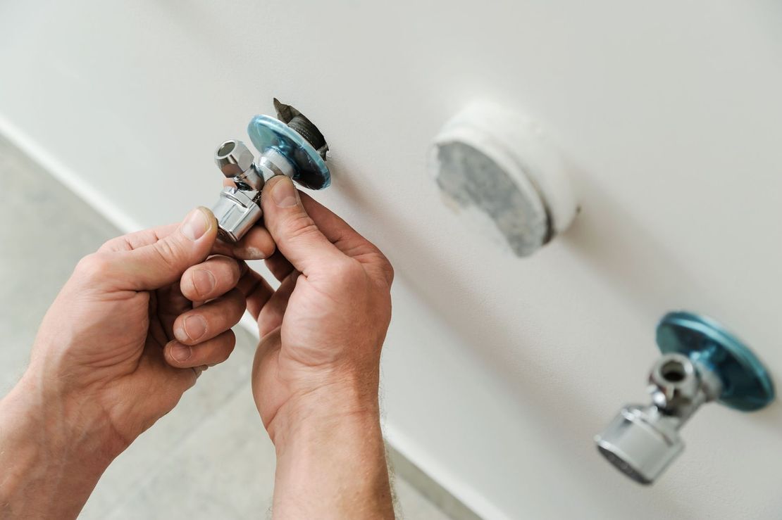 Una persona está arreglando un grifo en un baño.