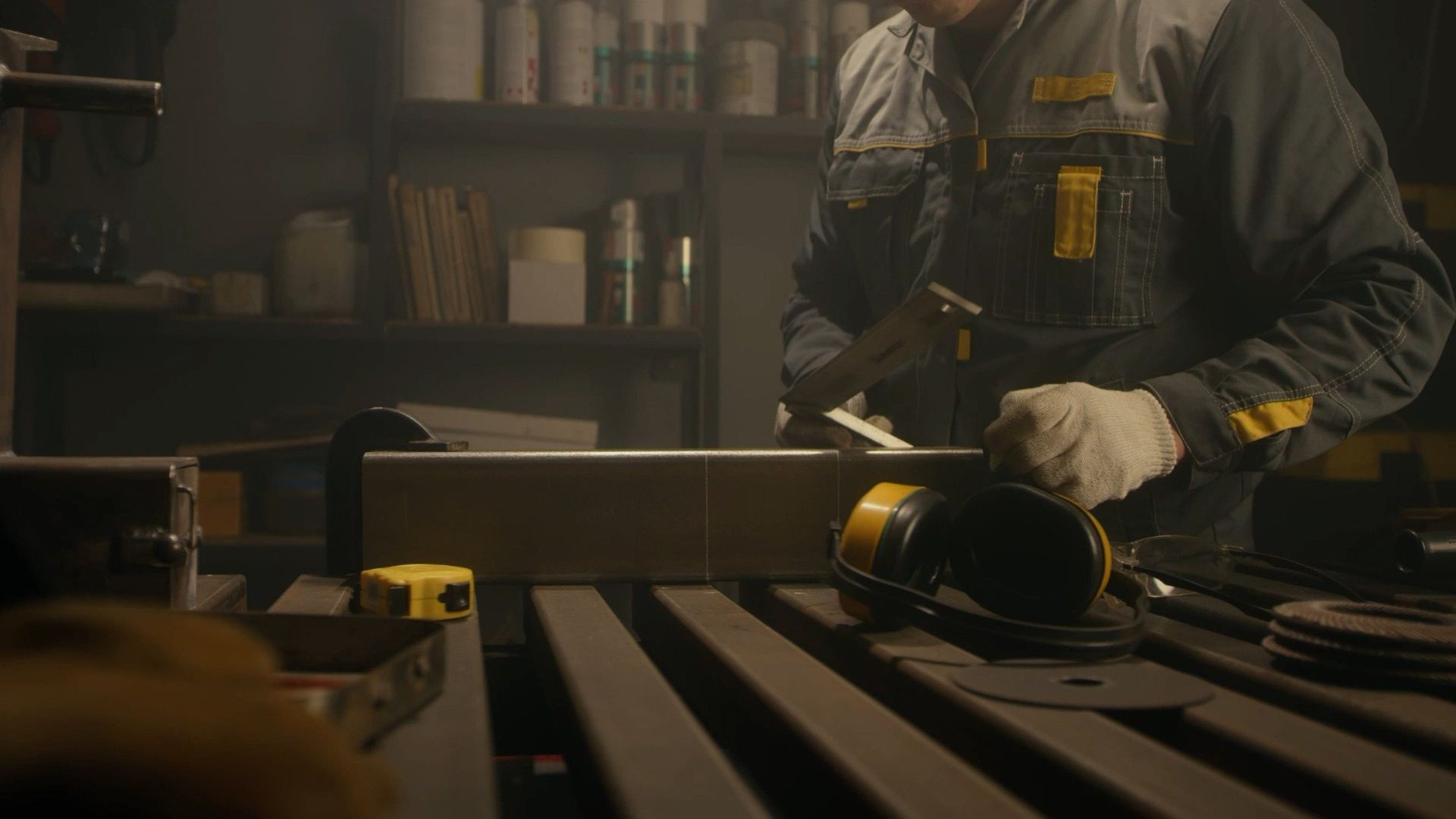 Un trabajador utiliza una sierra circular sobre un tablón de madera en un taller con poca luz.