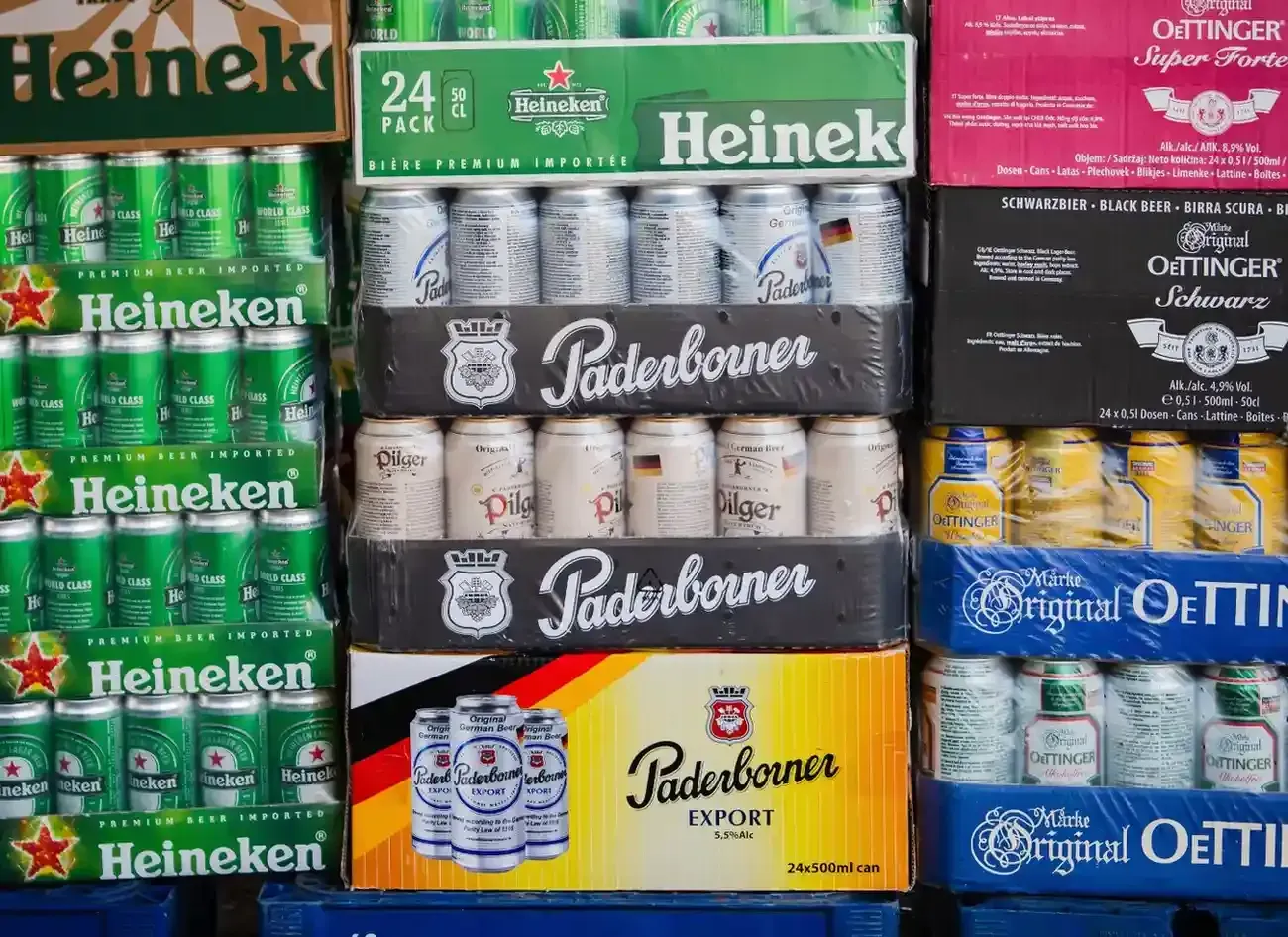Cajas apiladas de varias cervezas enlatadas, entre ellas Heineken, Paderborner y Oettinger.
