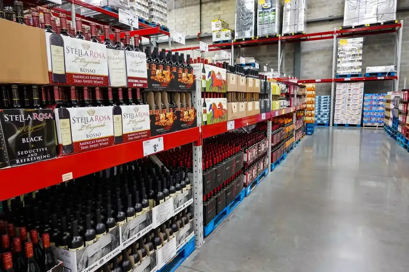 Estanterías de almacén repletas de filas de botellas de vino en cajas y envases de vidrio.