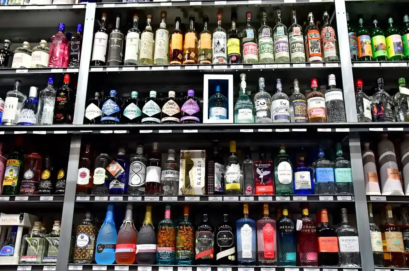 Estanterías repletas de botellas de vidrio de diversos licores, aguardientes y bebidas alcohólicas.