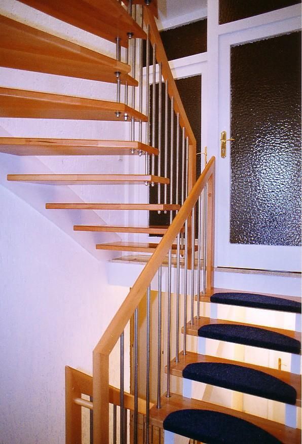 Eine Holztreppe mit einem schwarzen Teppich auf den Stufen