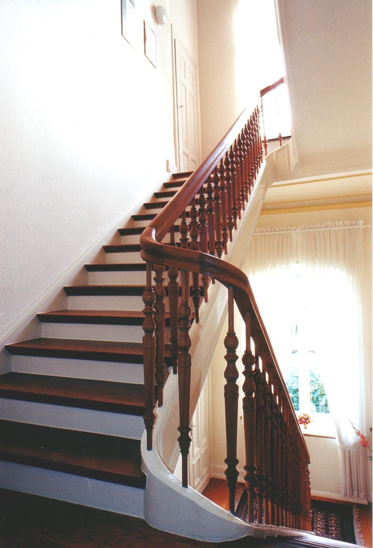 Eine Holztreppe mit weißen Stufen und einem Holzgeländer