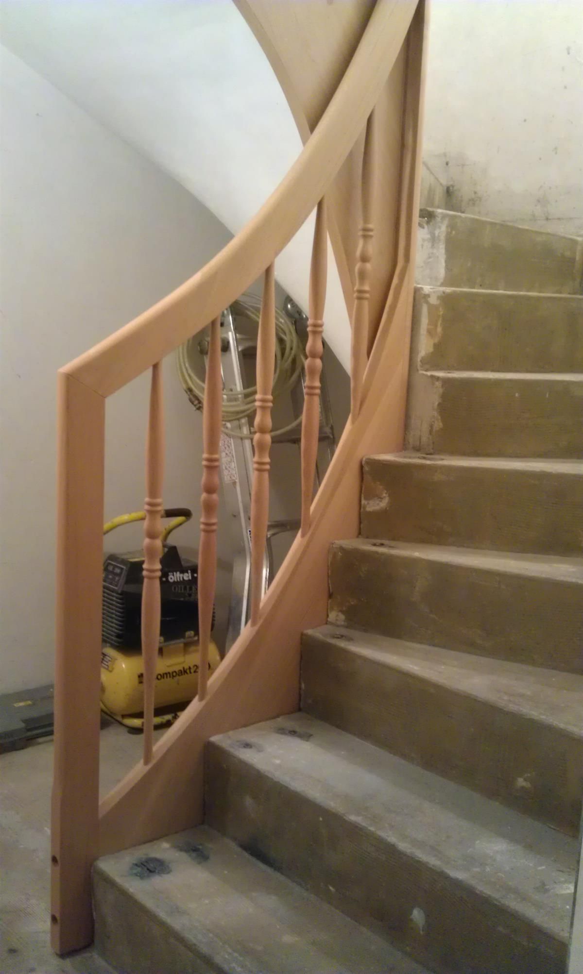 Eine Treppe mit einem Holzgeländer und einem gelben Luftkompressor