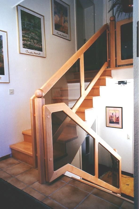 Eine Holztreppe mit einem Glasgeländer in einem Flur