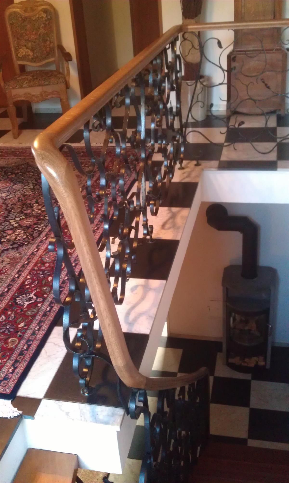 Eine Treppe mit schmiedeeisernem Geländer und kariertem Boden