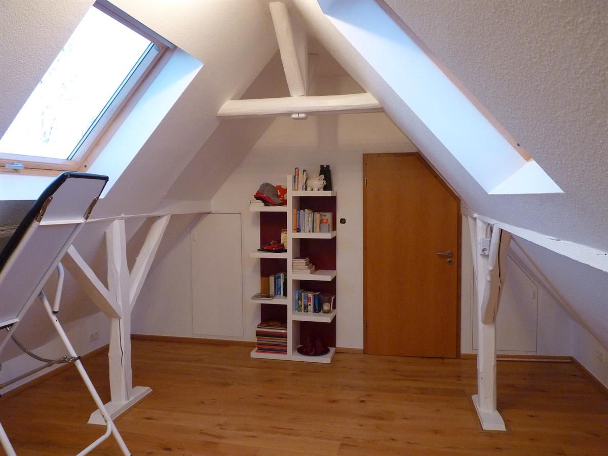 Ein Dachboden mit einem Regal voller Bücher und einer Tür