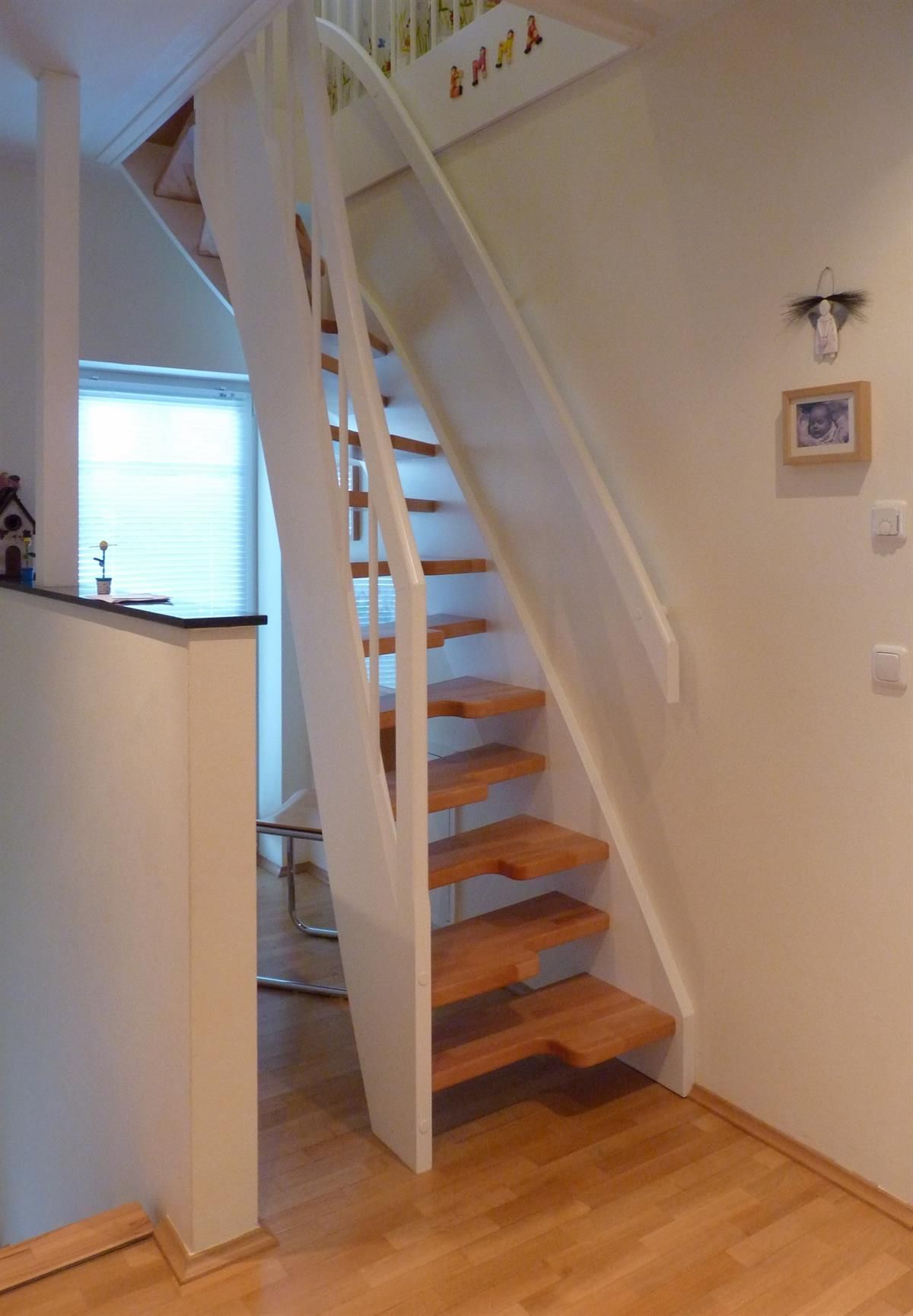 Eine Holztreppe mit einem weißen Geländer in einem Flur