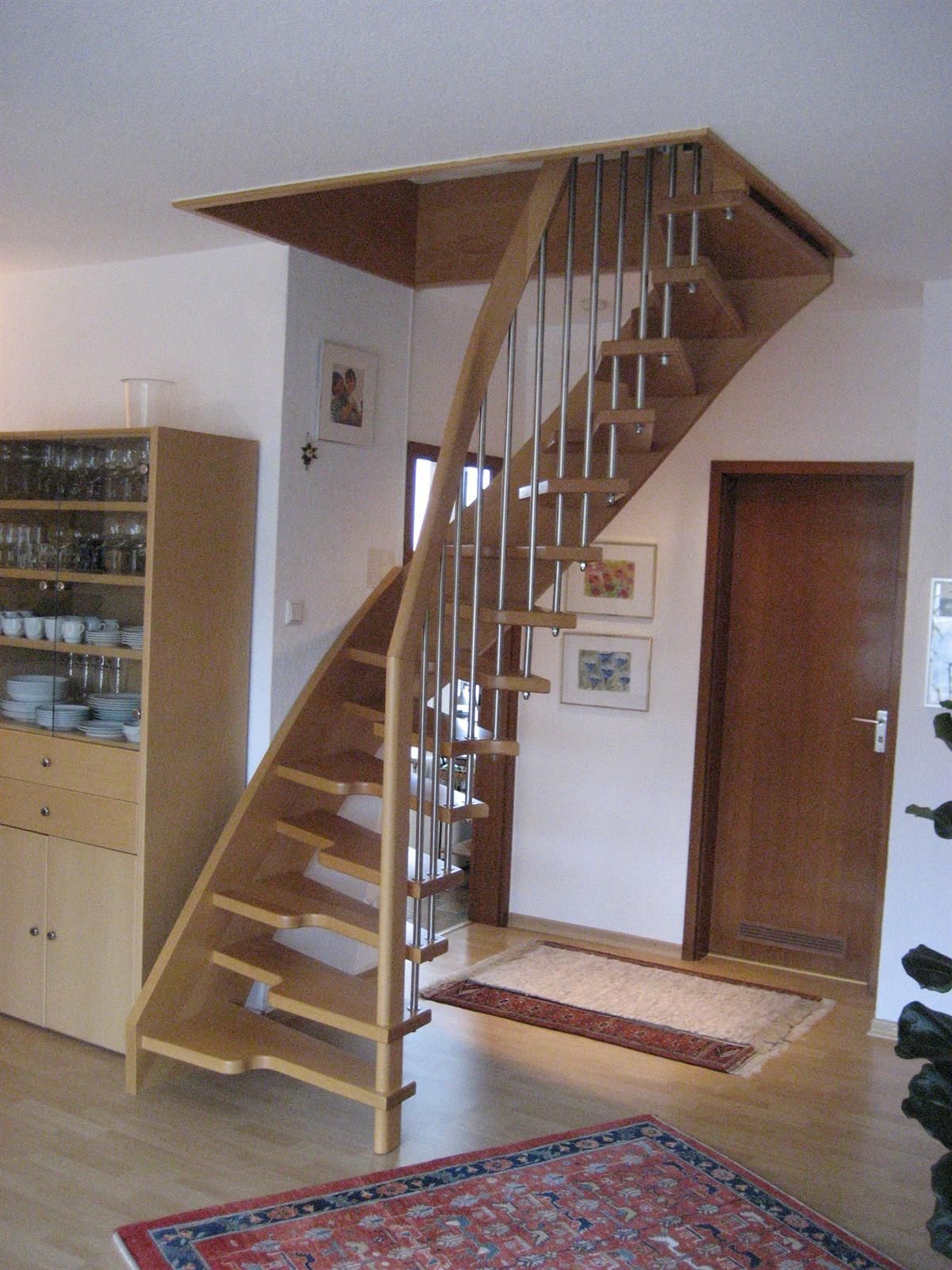 Eine Holztreppe in einem Wohnzimmer mit einem Teppich auf dem Boden