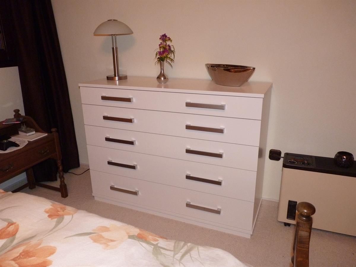 Ein Schlafzimmer mit einer weißen Kommode und einer Lampe
