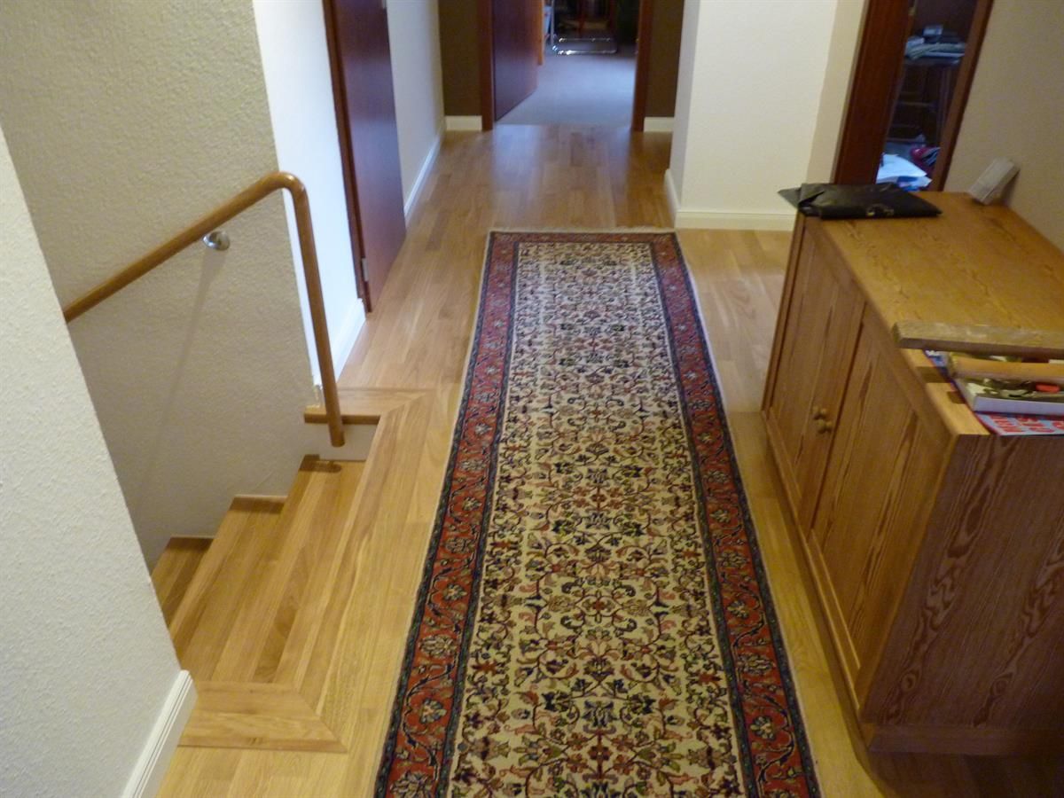 Ein Flur mit Treppe und einem Teppich auf dem Boden