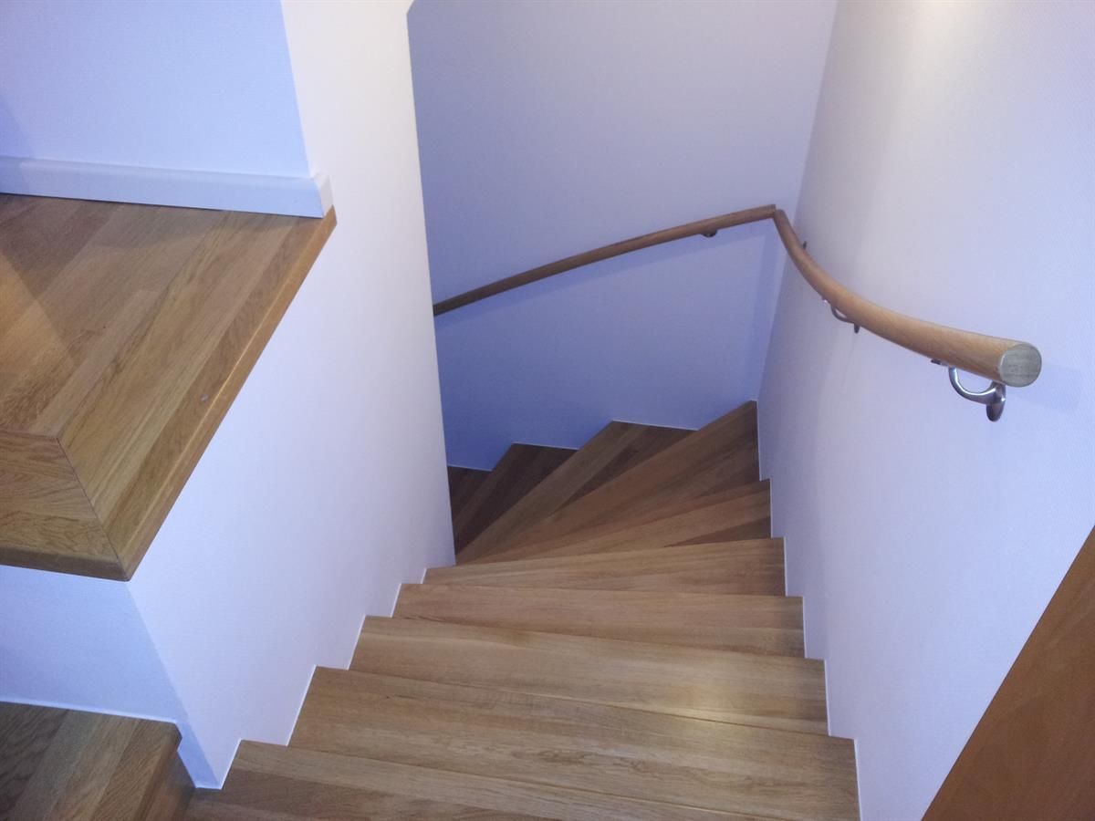 Eine Holztreppe mit einer weißen Wand und einem Holzhandlauf