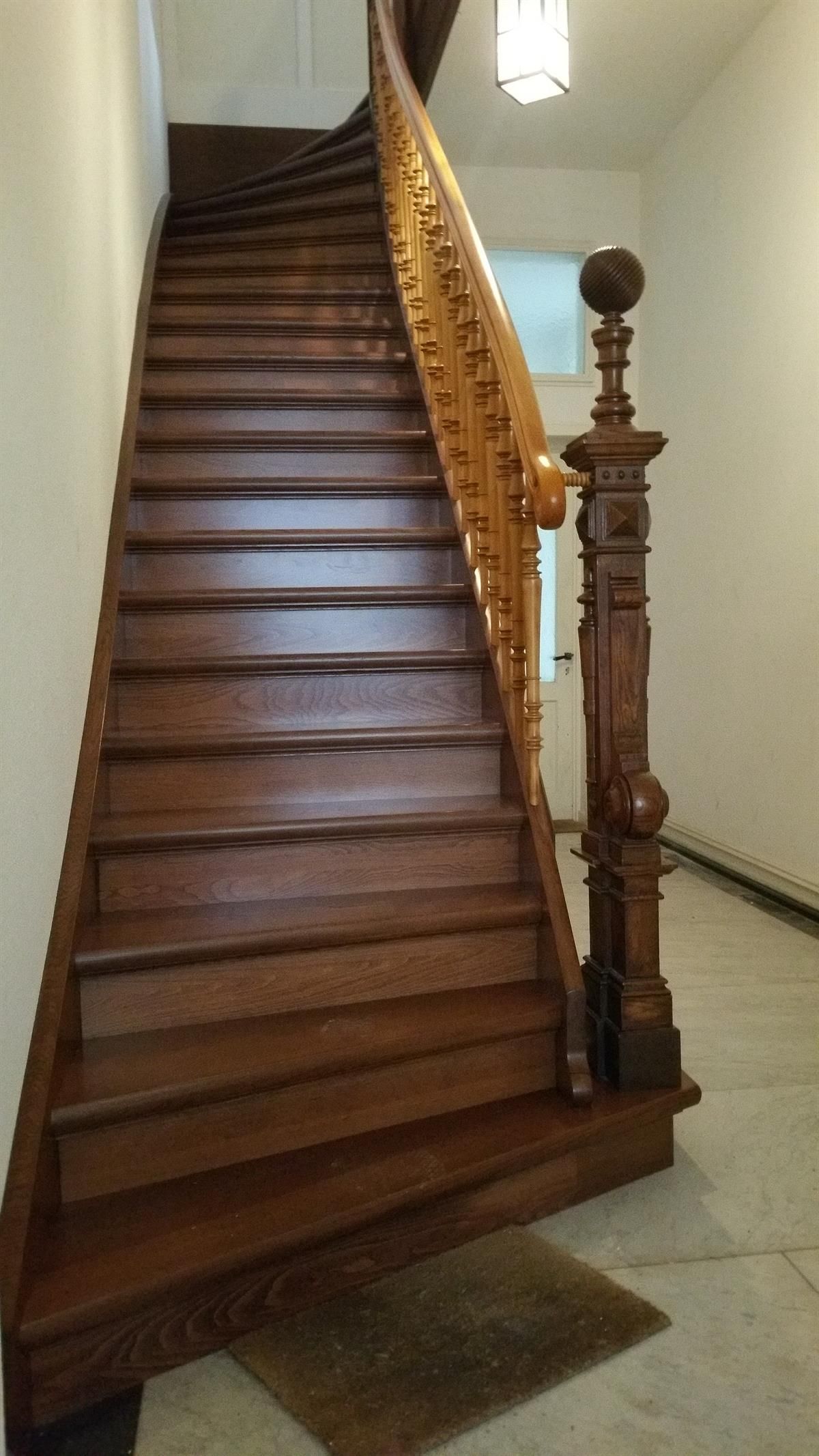 Eine Holztreppe mit einem ausgefallenen Geländer in einem Flur