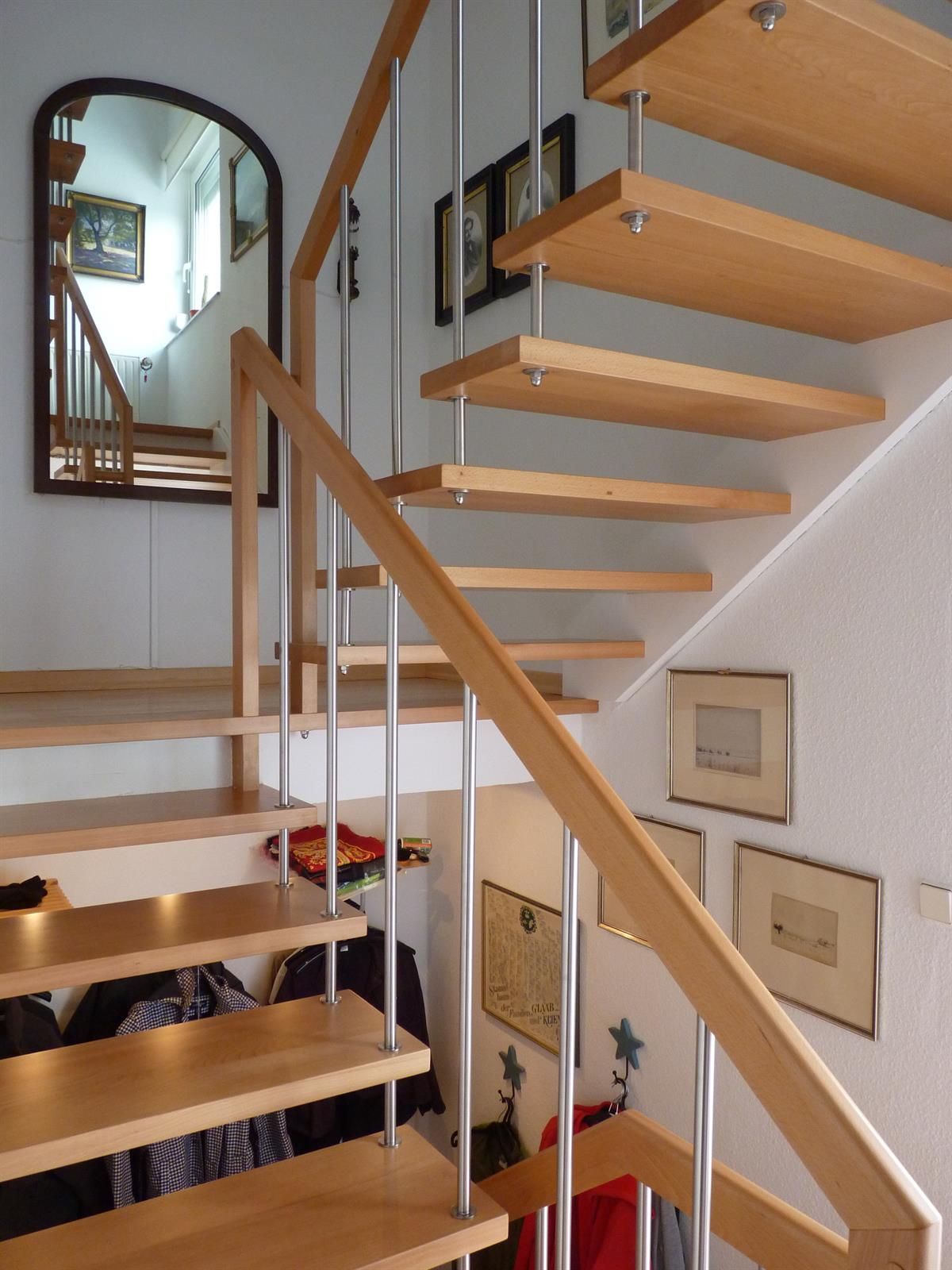 Eine Holztreppe mit einem Metallgeländer und einem Spiegel an der Wand