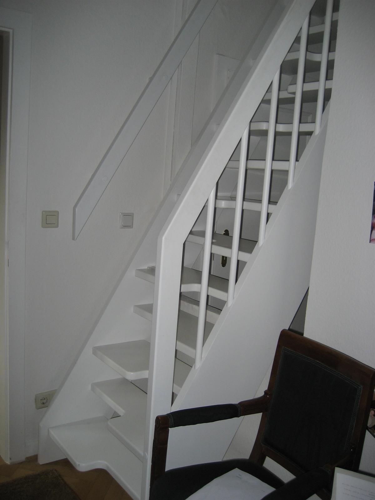 Eine weiße Treppe mit einem schwarzen Stuhl davor