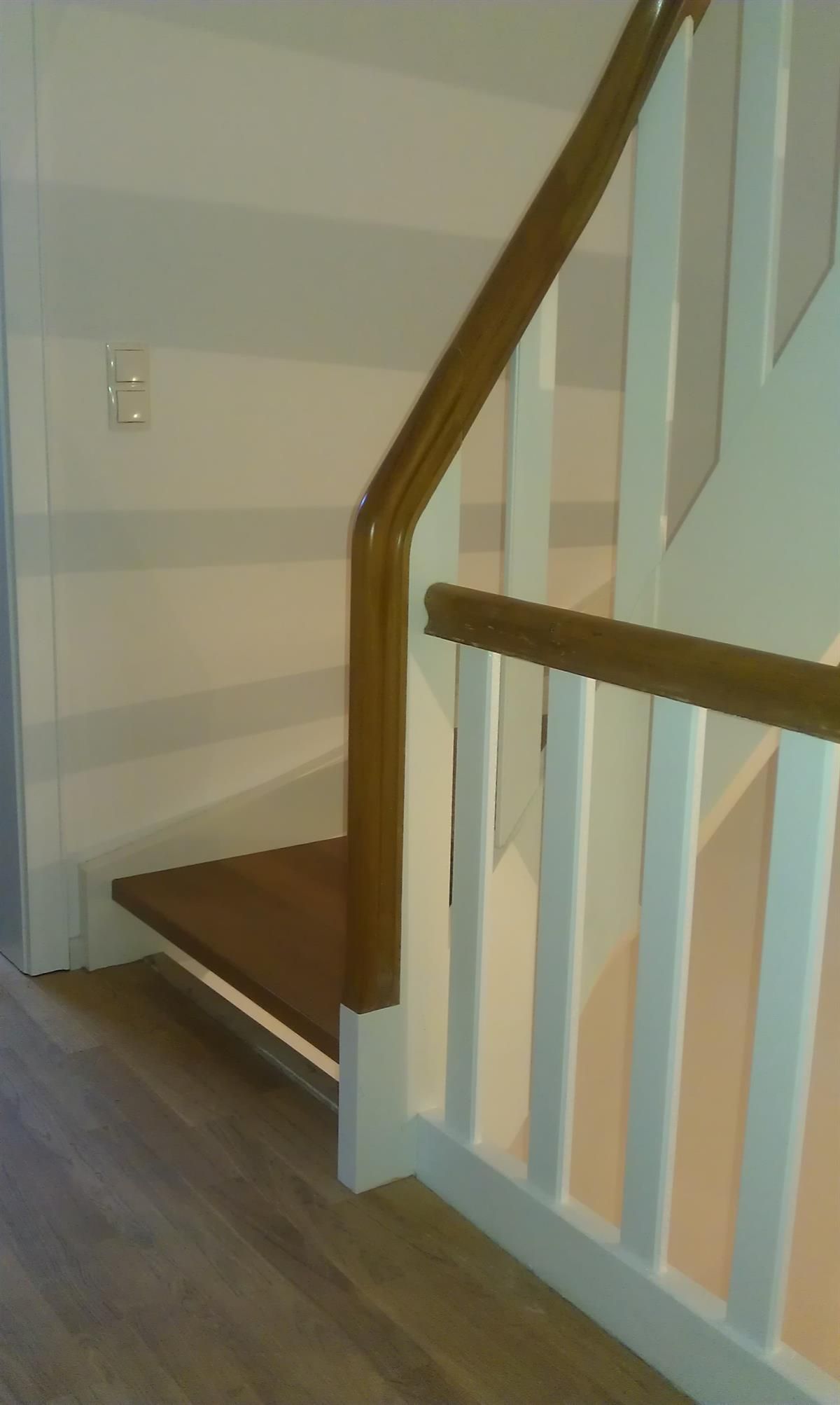 Eine Treppe mit einem weißen Geländer und einem Holzhandlauf