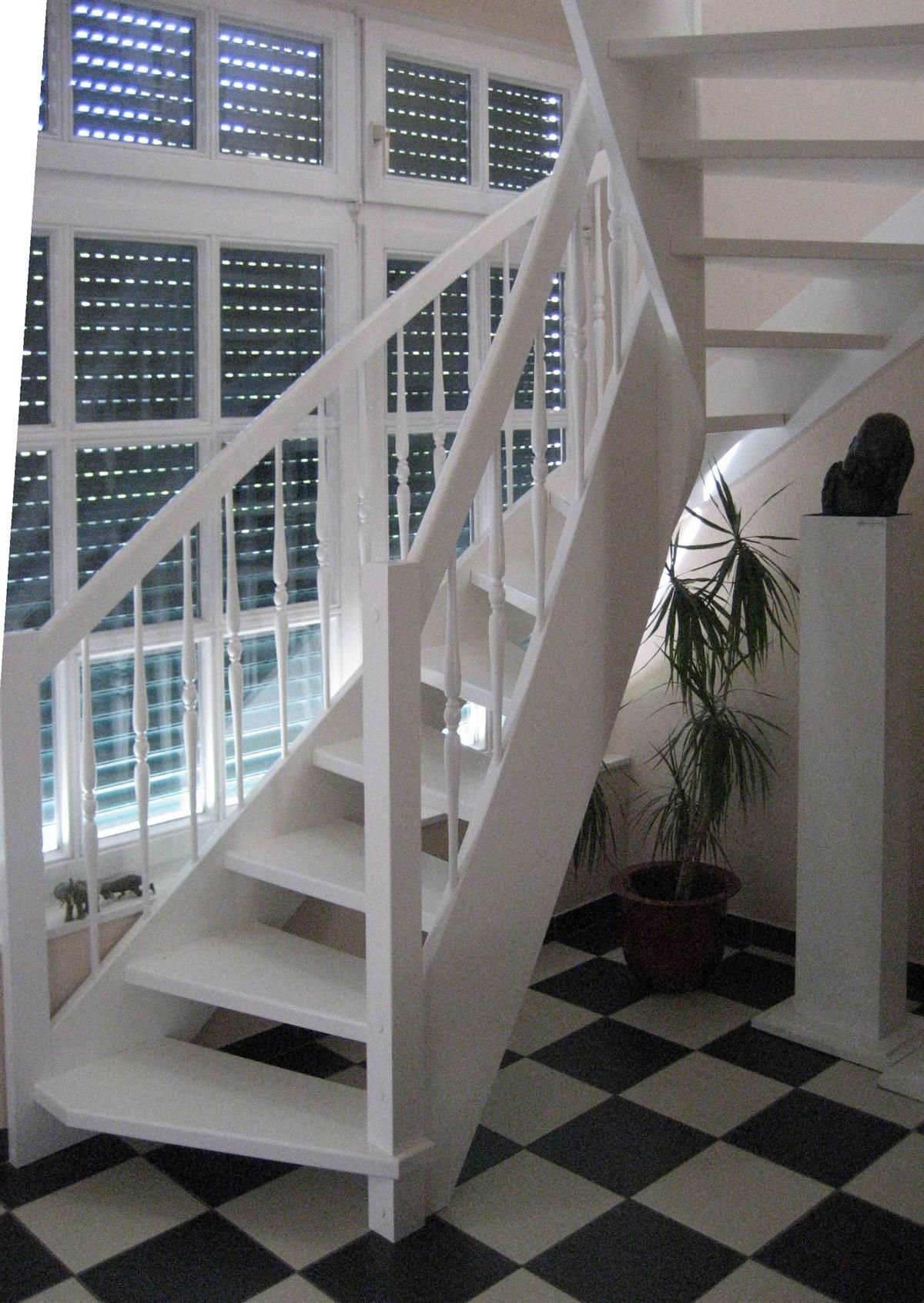 Eine weiße Treppe mit einem schwarz-weiß karierten Boden