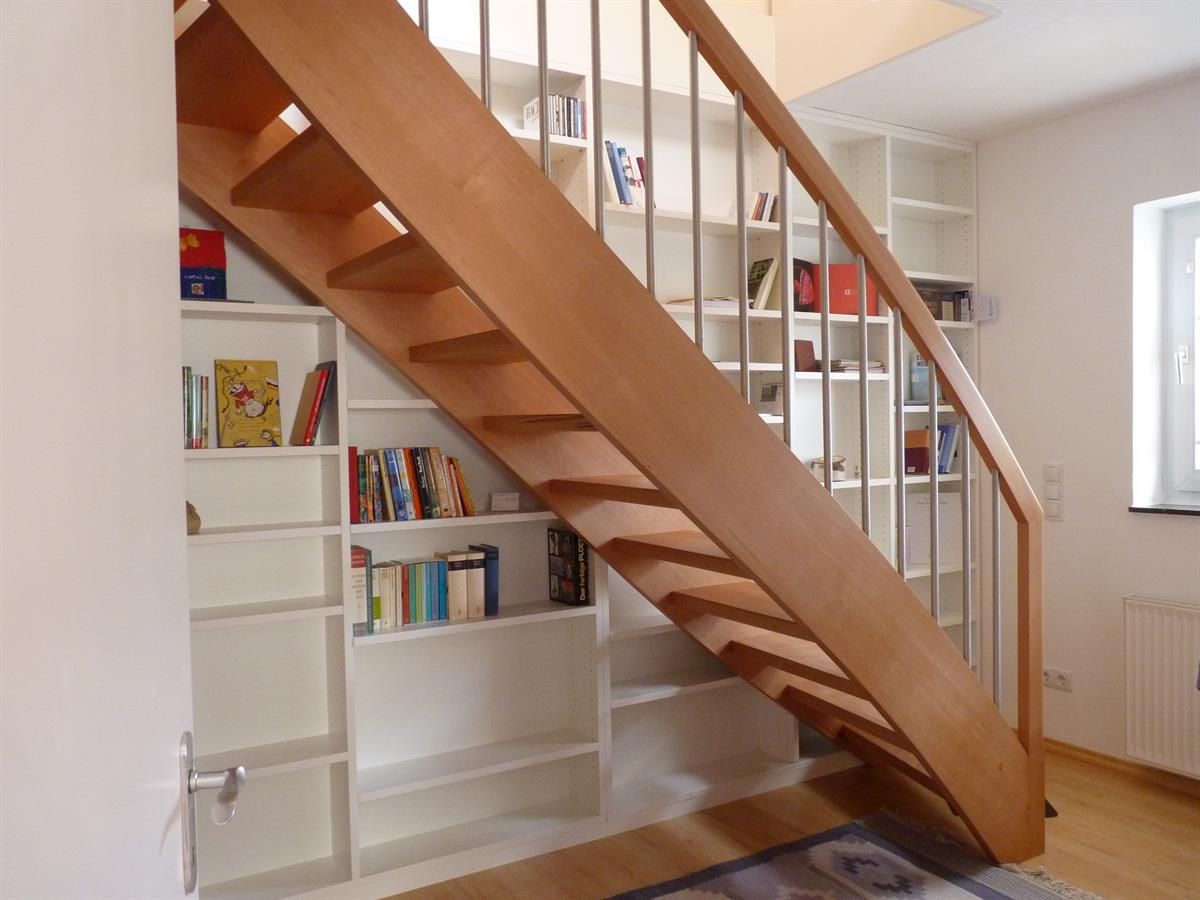 Eine Holztreppe in einem Raum mit Bücherregalen
