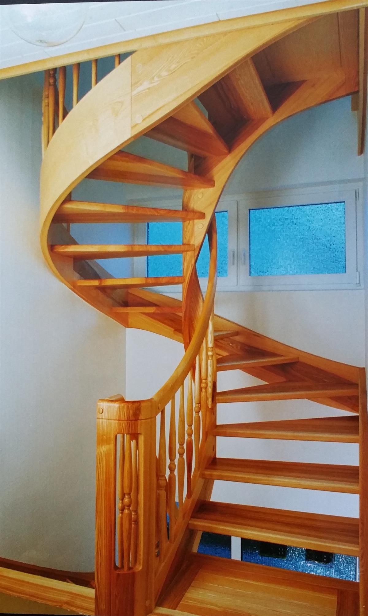 Eine hölzerne Wendeltreppe mit einem Fenster im Hintergrund