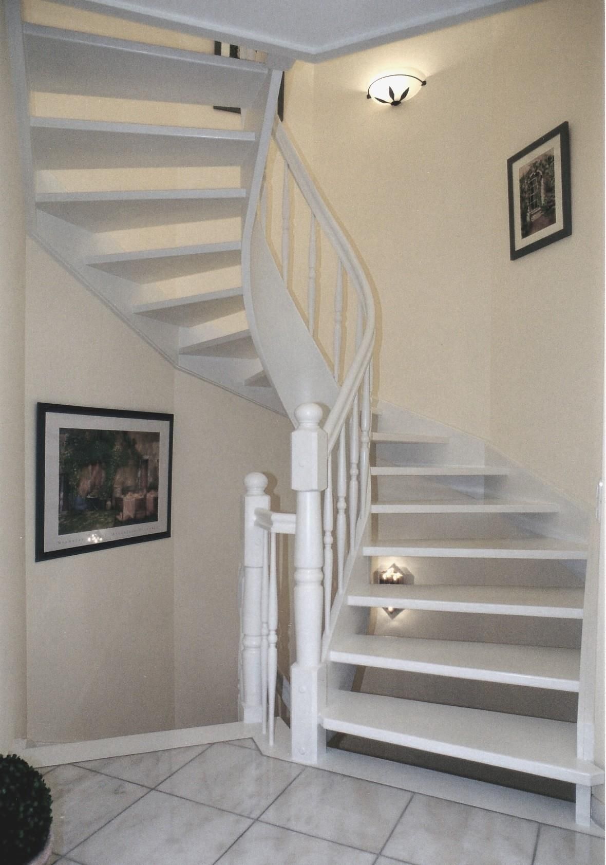 Eine weiße Wendeltreppe mit einem Bild an der Wand darüber