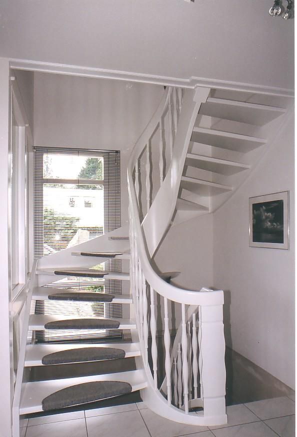 Eine weiße Wendeltreppe mit schwarzen Stufen führt in den zweiten Stock