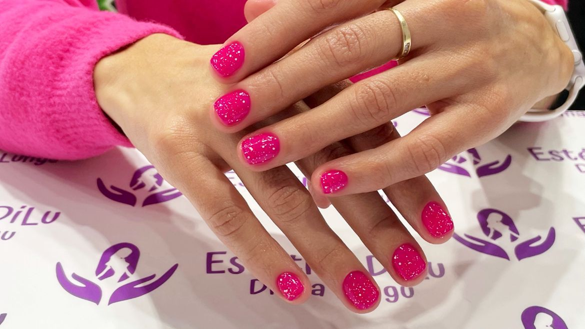 Un primer plano de las manos de una persona con uñas rosadas.