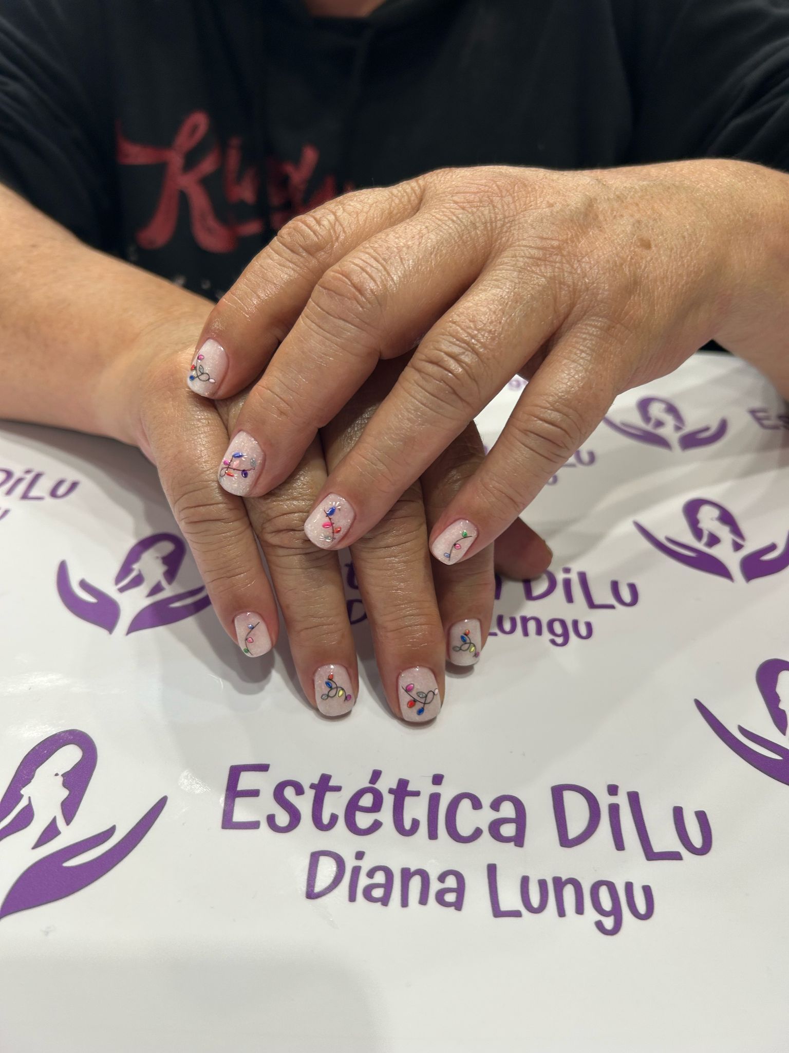 Las manos de una mujer están sobre una mesa con un cartel que dice estetica dillu diana lungu