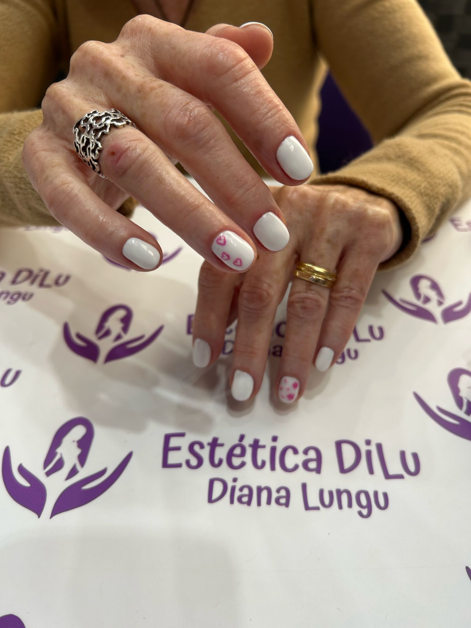 Una mujer está sentada en una mesa con sus manos sobre un cartel que dice estetica dilu diana lungu