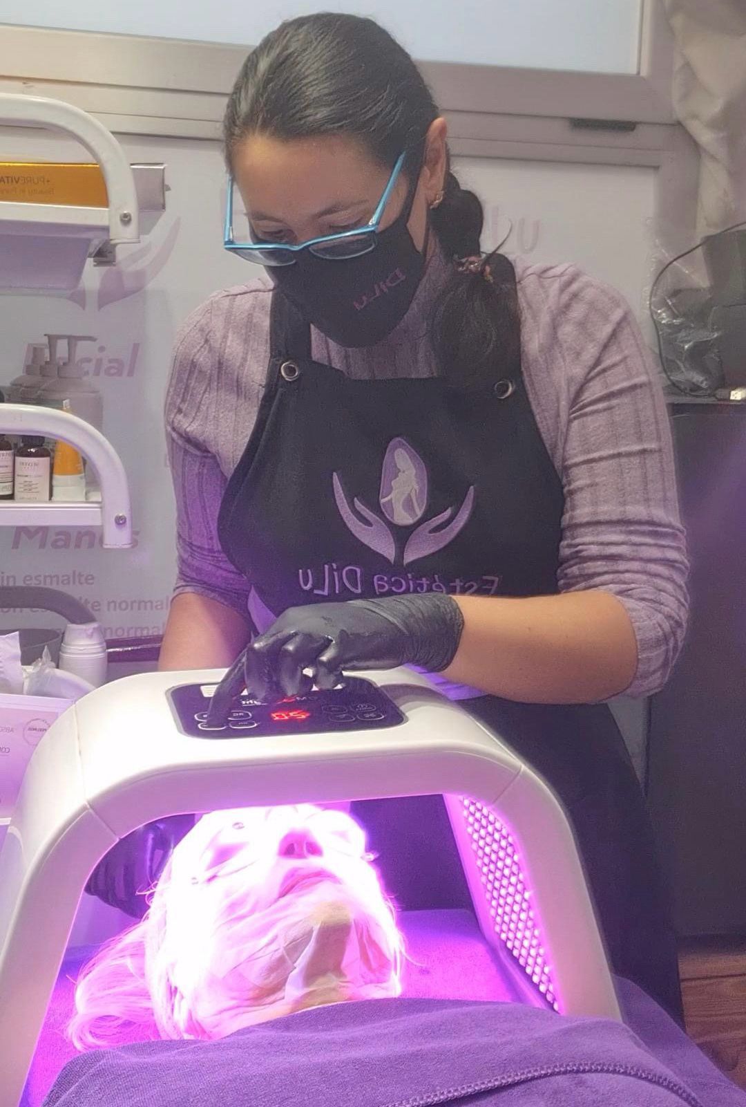 Una mujer que lleva una máscara está usando una máquina en la cara de una persona.