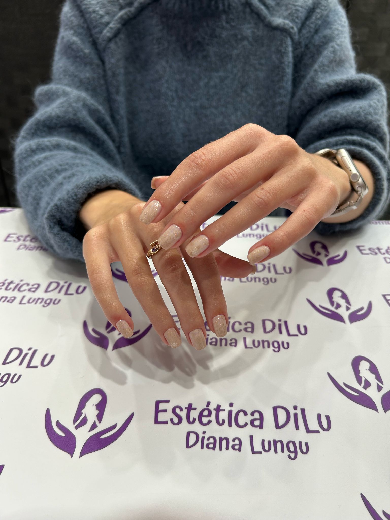 Una mujer está sentada en una mesa con sus manos sobre un trozo de papel que dice estetica dilu diana lungu.