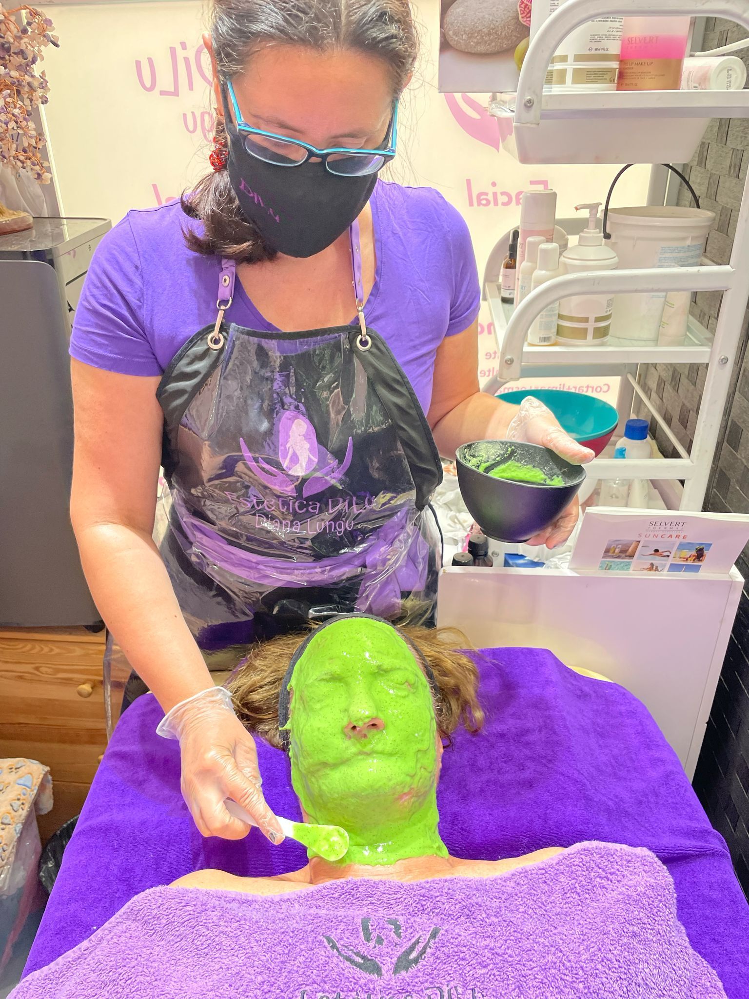 Una mujer está aplicando una máscara verde en la cara de una mujer.